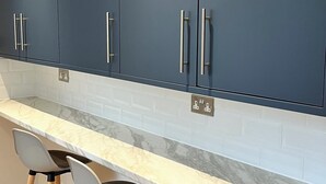 Una cocina moderna con armarios azul oscuro, una encimera de mármol y dos taburetes de bar.