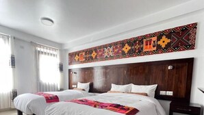 Ett hotellrum med två sängar, en sänggavel i trä och en dekorativ väggdekoration.