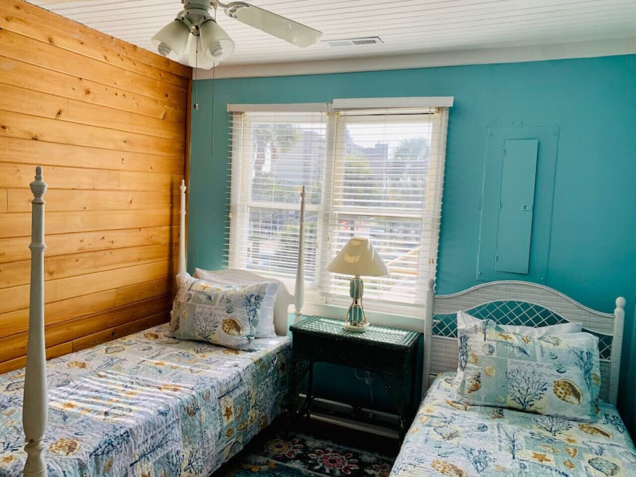 Un dormitorio con dos camas individuales, un ventilador de techo y una ventana con persianas.