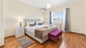 Un dormitorio con cama, mesita de noche, lámpara y ventana con cortinas.
