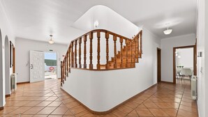 Un interior espacioso con una escalera curva, suelo de baldosas y vistas al exterior.