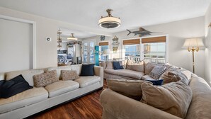 Ein geräumiges Wohnzimmer mit zwei beigen Sofas, Holzboden und einem großen Fenster mit Blick.