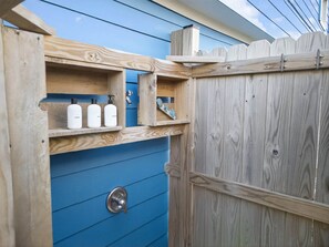 A wooden gate with a blue door, a metal lock, and a shelf with bottles. - Cozy Cottage - Dog friendly, Near the Beach! (Galveston)