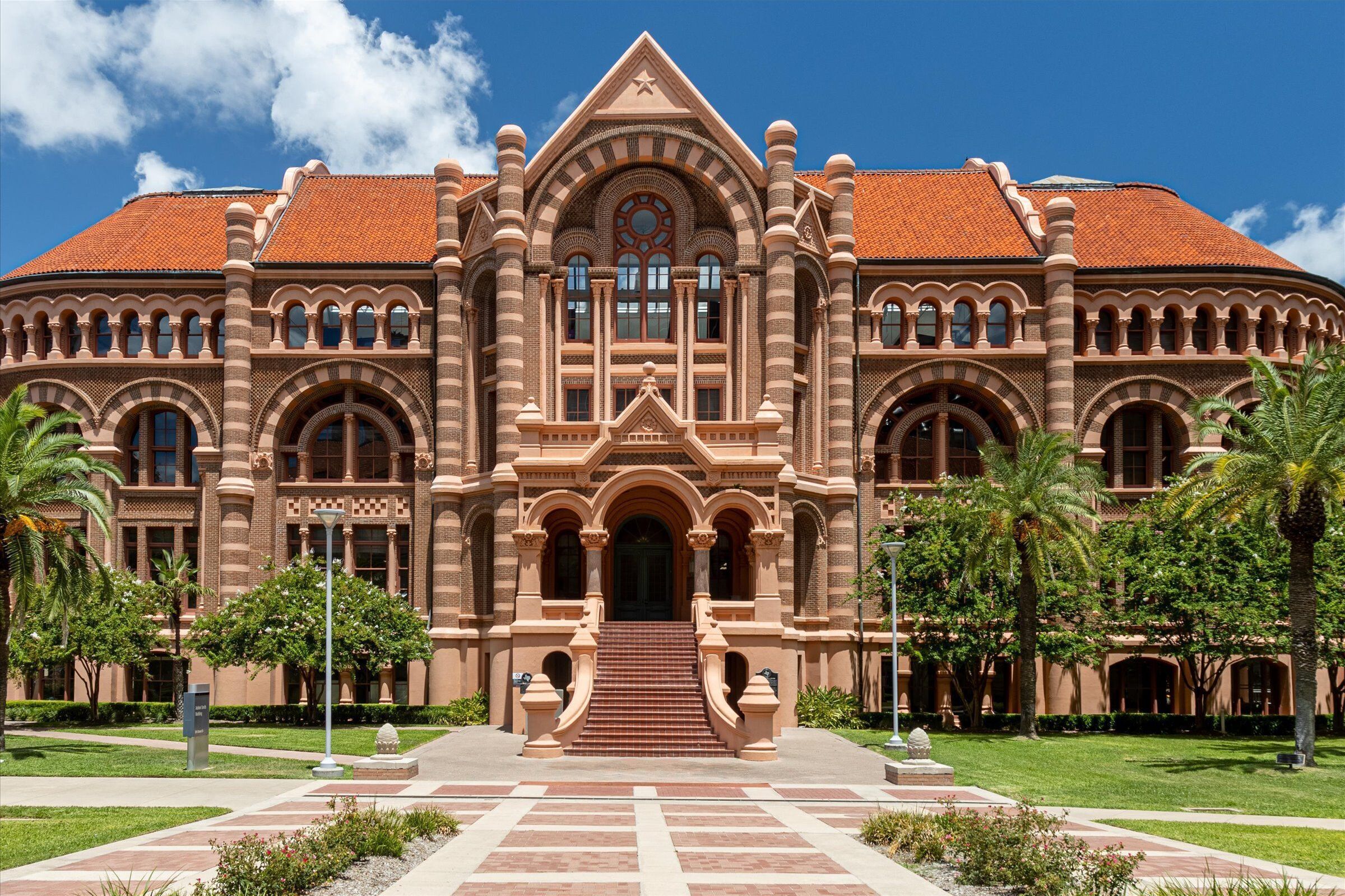 A large, historic building with a symmetrical facade, arched windows, and a central entrance with steps.