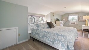 Une chambre à coucher avec un lit, une commode, une chaise et une fenêtre avec des rideaux.