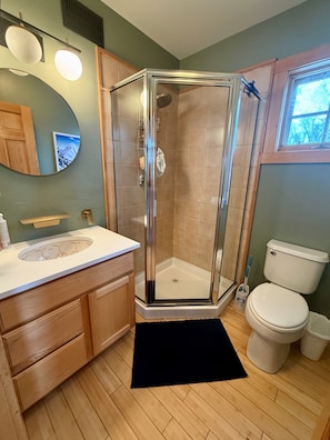 Ein Badezimmer mit Duschkabine, Toilette, Waschbecken mit Spiegel und HolzschrÀnken.
