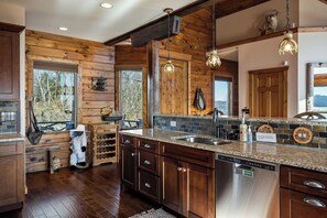 Una cocina con paredes de madera, encimera de granito, electrodomésticos de acero inoxidable y vistas al exterior.