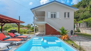 Ein zweistöckiges Haus mit Schwimmbad, überdachter Terrasse und einer Treppe, die zum Obergeschoss führt.
