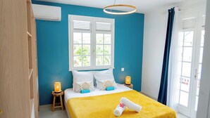 Ein Schlafzimmer mit Bett, Fenster, Tür und Nachttisch mit Lampe.