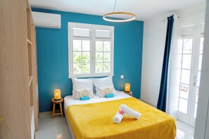 A bedroom with a bed, a window, a door, and a bedside table with a lamp. - Villa Rose du Désert: luxury, conviviality, swimming pool and nearby beaches (Sainte-Anne)