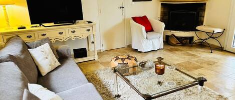 A living room with a sofa, a coffee table, a television, a fireplace, and a lamp.