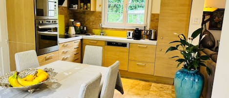 Cozinha moderna com área de refeições, equipada com forno embutido, micro-ondas e uma grande janela.