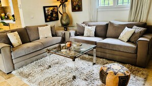 Ein Wohnzimmer mit zwei Sofas, einem Glastisch, einem Teppich und einer dekorativen Schale.