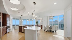 A modern kitchen with a central island, recessed lighting, and large windows. - Turquoise C2509 (Orange Beach)