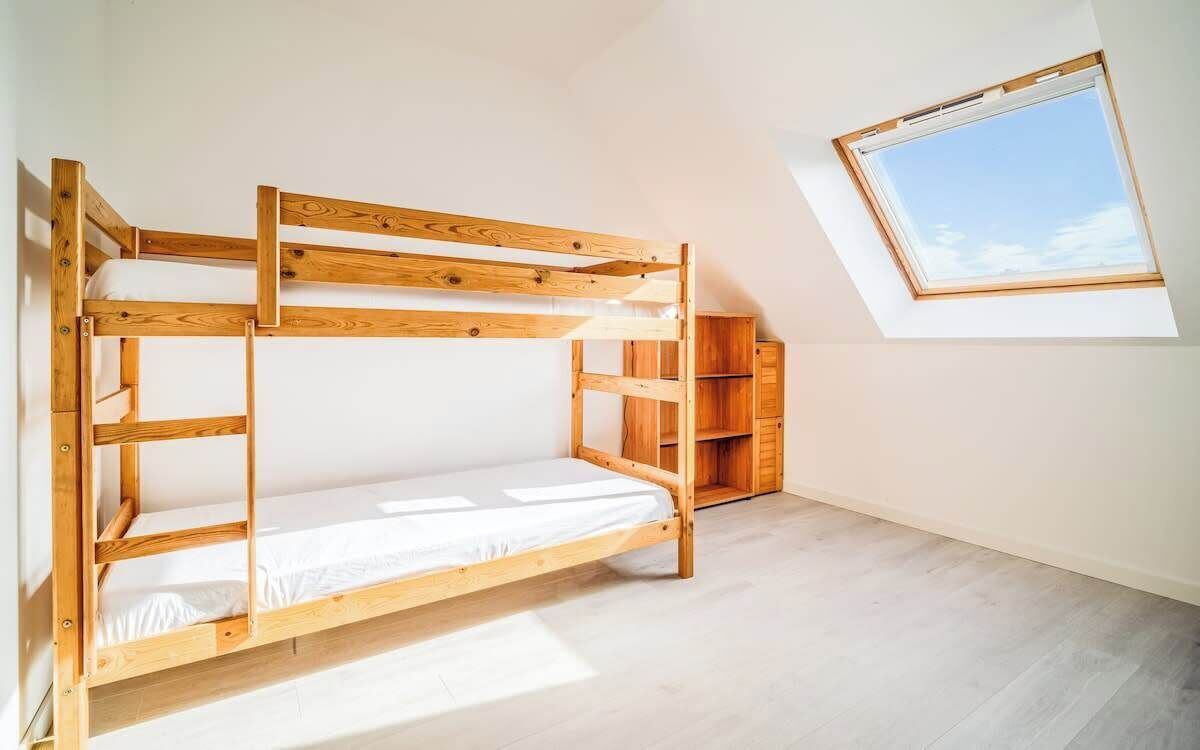 Ein Schlafraum mit Etagenbetten, einem Dachfenster und eingebauten Regalen.