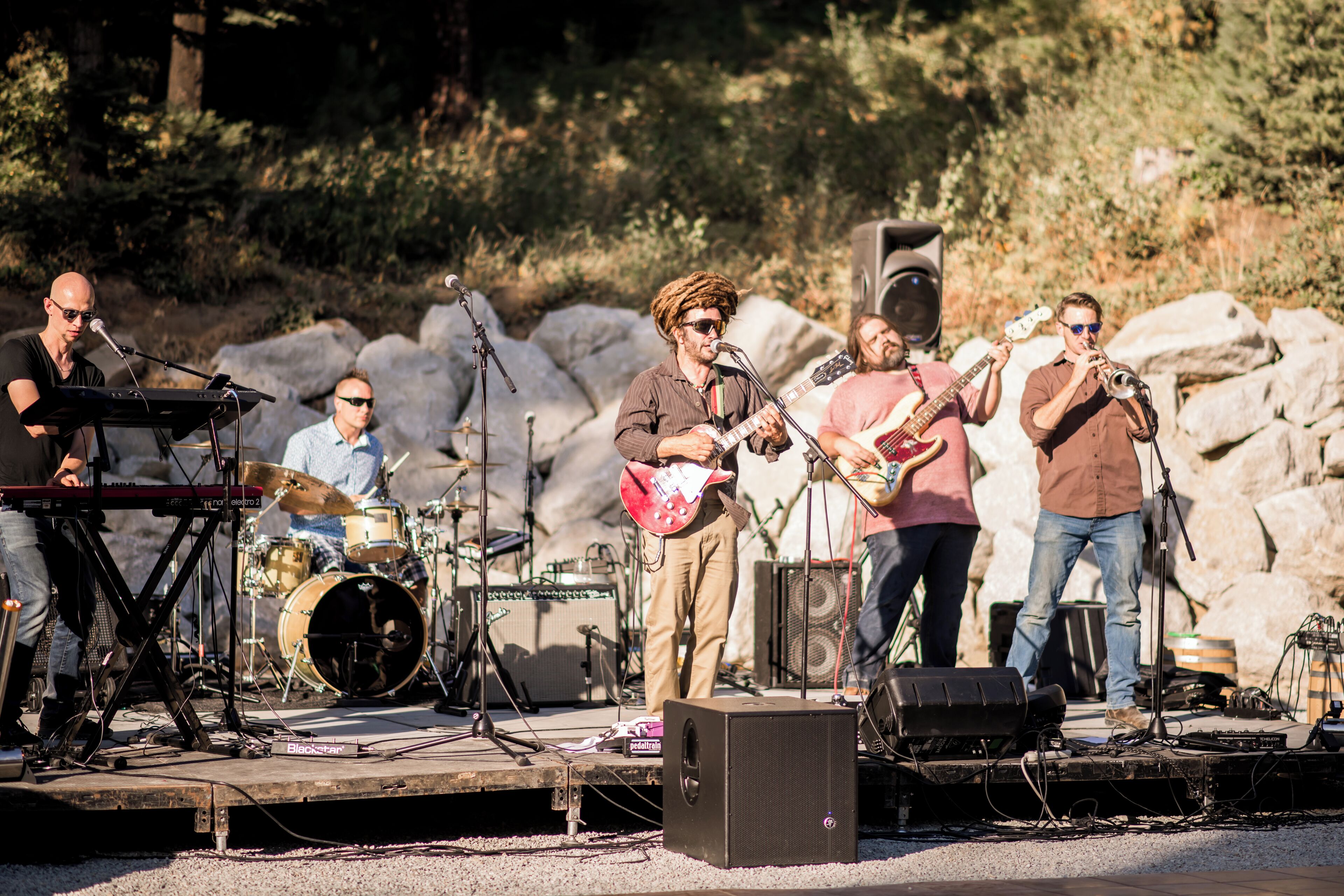 A band performing on an outdoor stage with musical instruments and equipment.