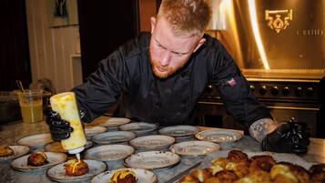 A chef preparing food in a kitchen with stainless steel appliances and a marble countertop.