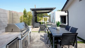 An outdoor patio area with a barbecue grill, seating, and a pergola. - Velvet Spur | Designer Stay in Old Town! Walkable (Scottsdale)