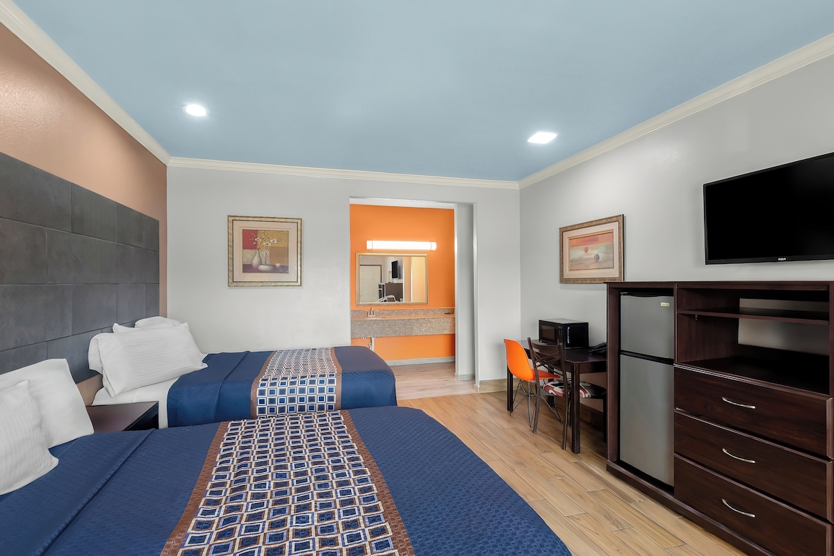 A hotel room with a bed, a desk, a chair, a television, and a refrigerator.