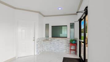 A hallway with a white door, a stone accent wall, a red bench, and a window with a view of greenery.