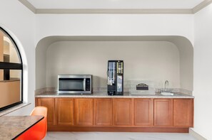A compact kitchen with a microwave, coffee maker, and a breakfast sign. - Downtowner Inns & Suites IAH Airport-Humble  (Humble)