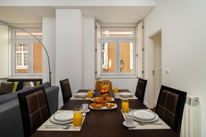 Ein Essbereich mit einem für das Frühstück gedeckten Tisch, darunter Croissants und Orangensaft, mit Blick auf die Straße.