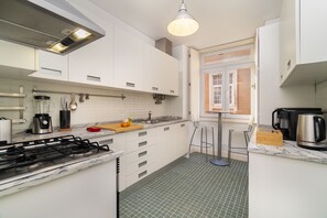 Eine moderne Küche mit weißen Schränken, einem Gasherd, einer Kaffeemaschine und einem Fenster mit Blick.