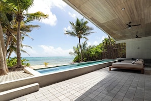 Un espace piscine avec vue sur l’océan, un plafond en bois et un lit avec des oreillers.