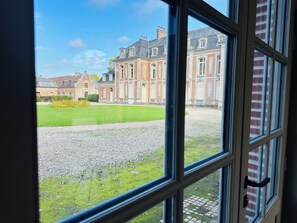 Une vue à travers la fenêtre d’un grand bâtiment historique donnant sur une cour intérieure.