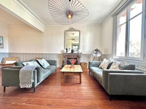 A living room with two grey sofas, a wooden coffee table, a fireplace, and a large window. - La Villa Dorange, 15 min from the beach- Famille-Amis (Sailly-Flibeaucourt)