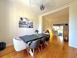 A dining area with a long table, four chairs, a vase with flowers, and a ceiling light fixture. - La Villa Dorange, 15 min from the beach- Famille-Amis (Sailly-Flibeaucourt)