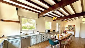 A kitchen with a large island, white cabinets, and a dining area with chairs.