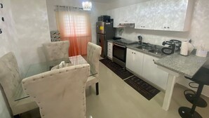 A compact kitchen with white cabinets, a stainless steel refrigerator, a built-in oven, and a granite countertop. - Lovely 2-bedroom apartment with AC in charming Bayahíbe 125 DOLARES POR NOCHE (Bayahíbe)