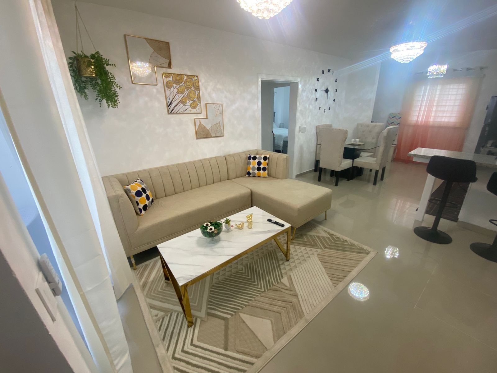 Ein modernes Wohnzimmer mit einem beigefarbenen Sofa, einem Couchtisch und einem Essbereich mit Stühlen und Tisch.