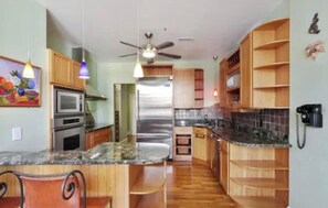 Eine Küche mit Holzausstattung, einem Kühlschrank, einer Mikrowelle und einem Deckenventilator.