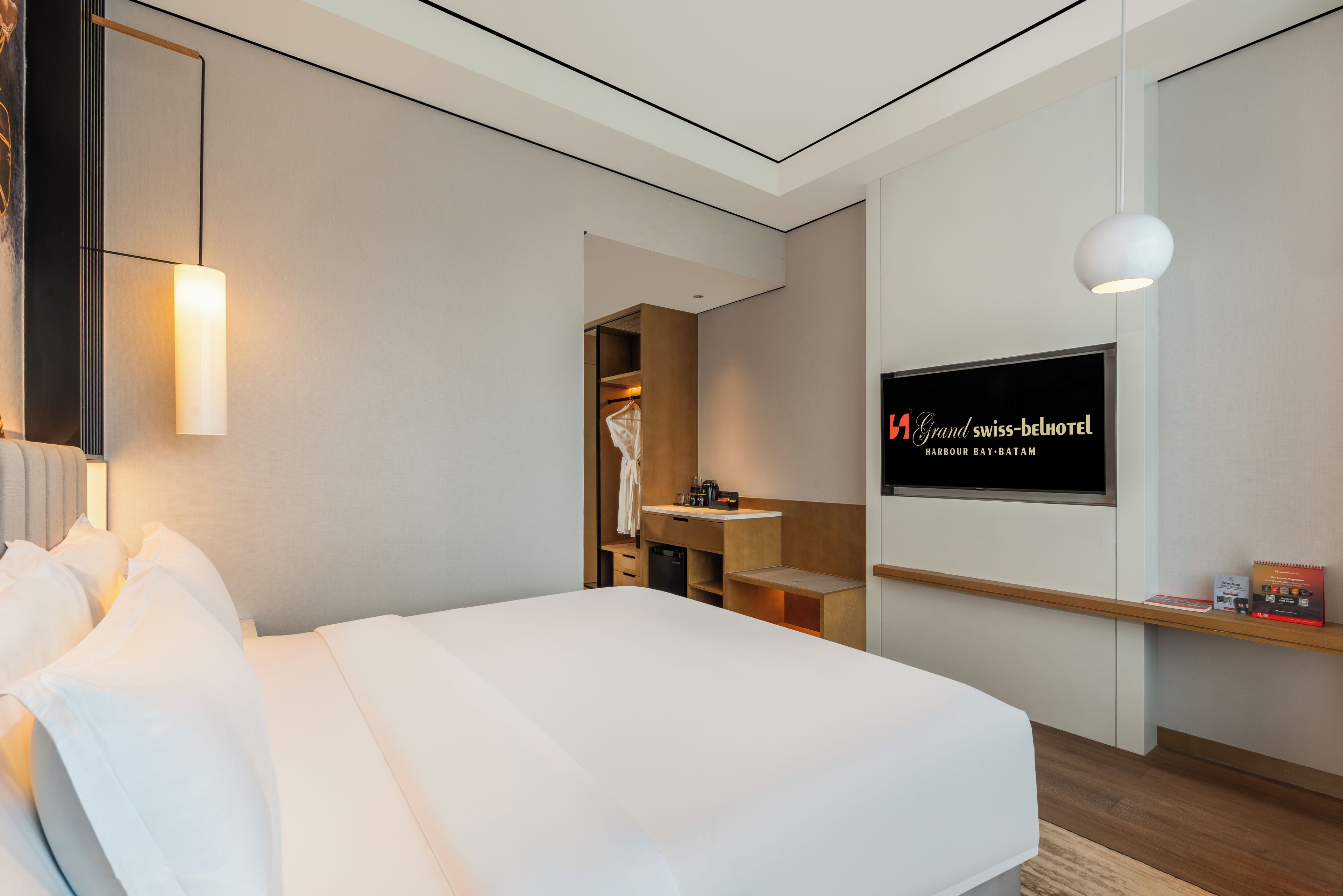 Une chambre d’hôtel équipée d’un lit, d’une télévision, d’un miroir et d’une armoire.