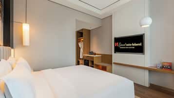 Une chambre d’hôtel équipée d’un lit, d’une télévision, d’un miroir et d’une armoire.
