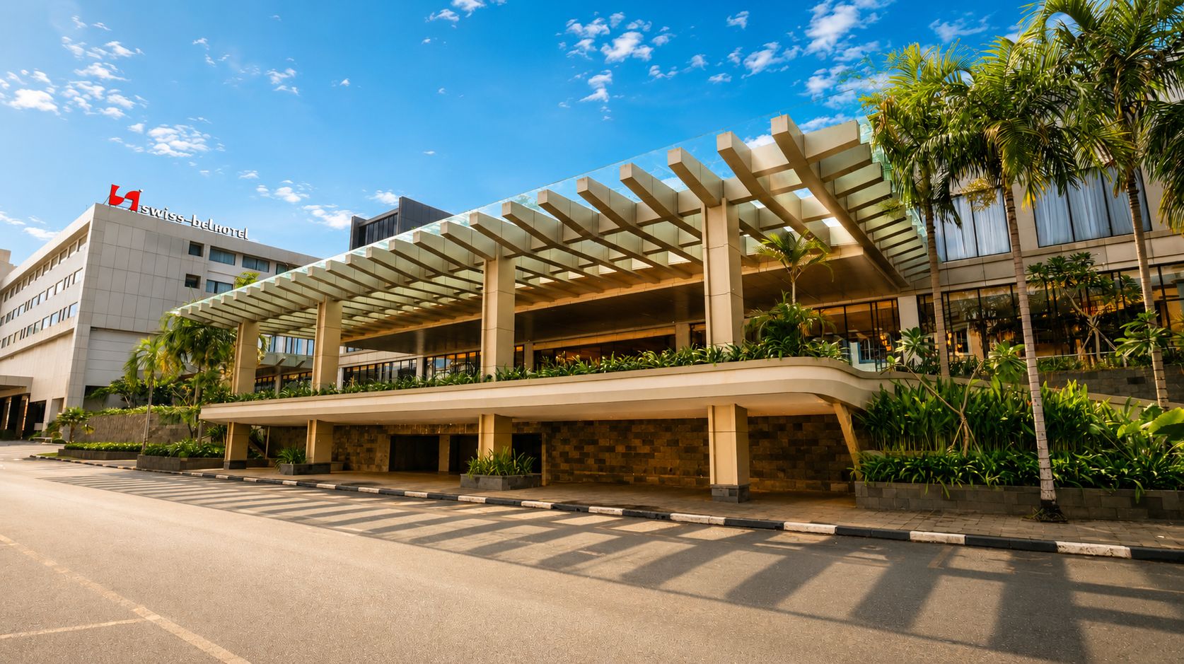 A hotel with a covered entrance, outdoor seating area, and a prominent Swiss logo.