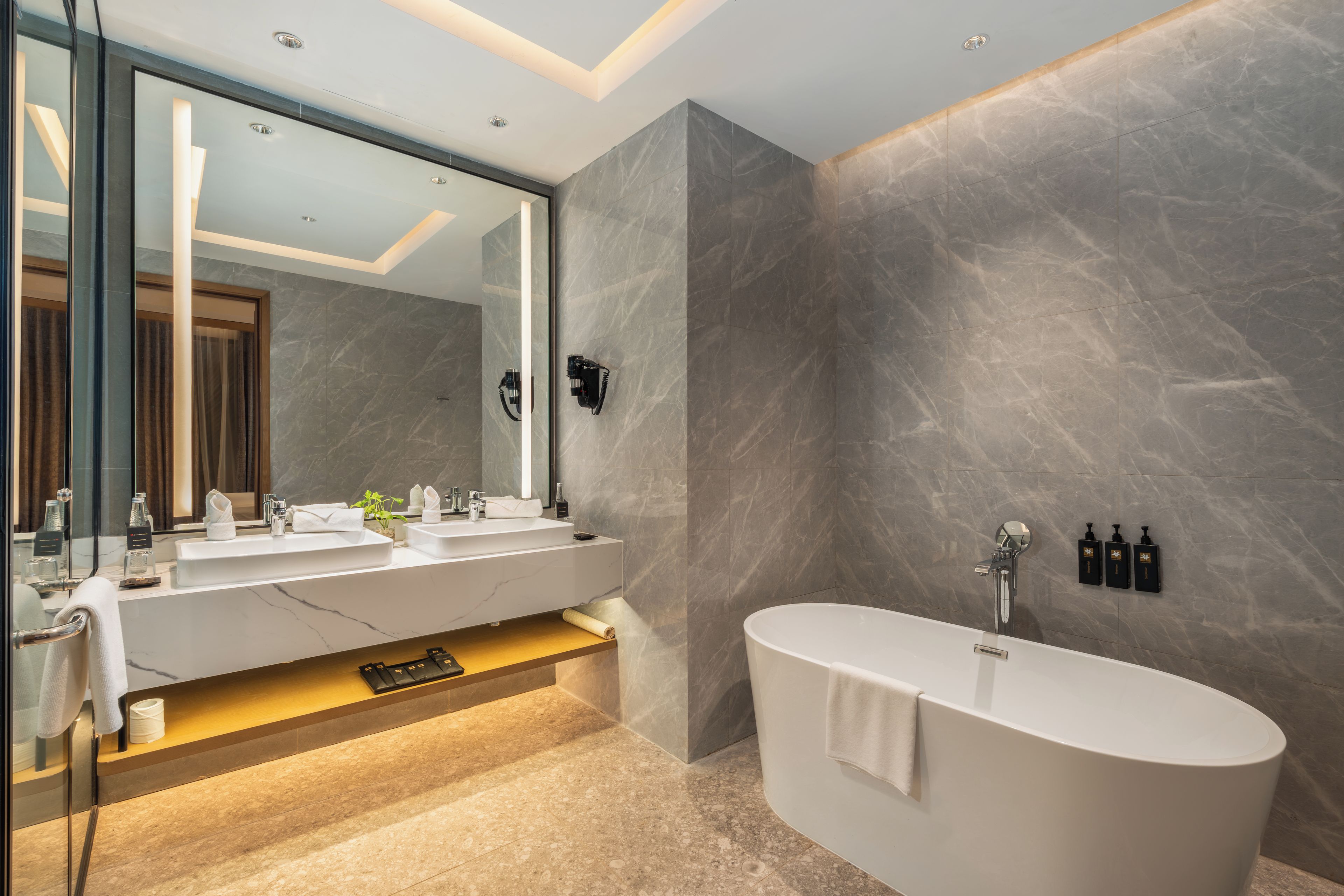 Une salle de bain moderne avec une baignoire sur pieds, un grand miroir et un meuble-lavabo doté de deux vasques.