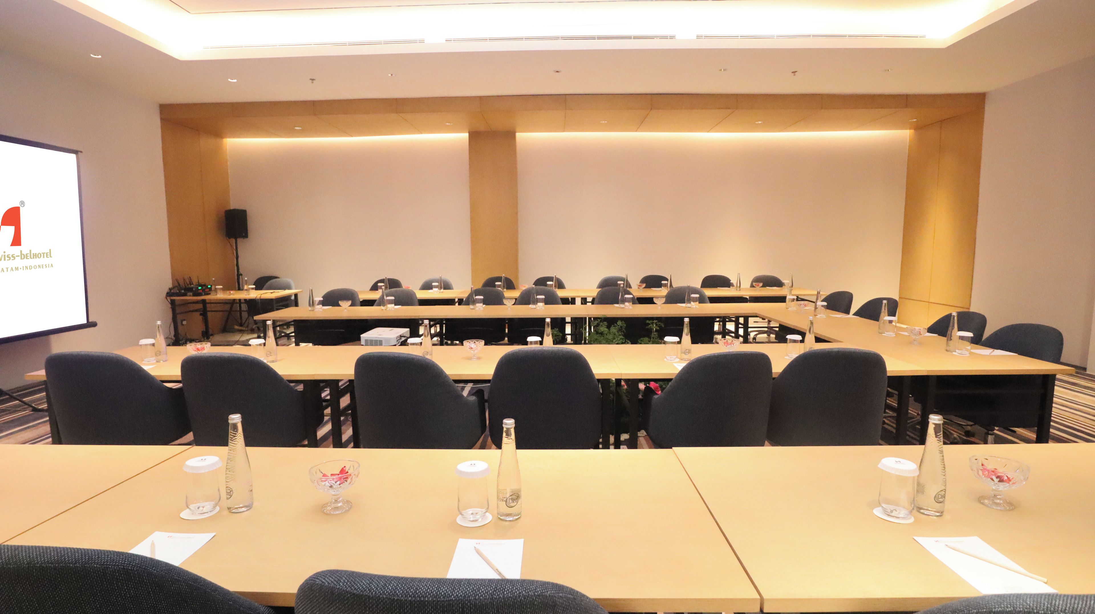Ett konferensrum med flera bord, stolar och en projektorduk.