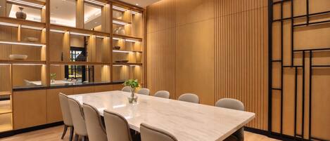 Un espace repas moderne avec une table en marbre, des chaises blanches et un mur revêtu de panneaux en bois.