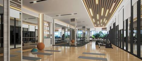 Un gimnasio amplio con equipo de ejercicio, suelo de madera y ventanas grandes.