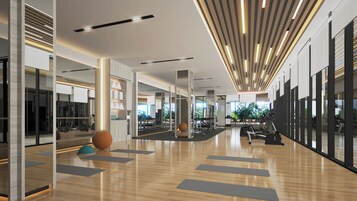 A spacious gym with exercise equipment, wooden flooring, and large windows.