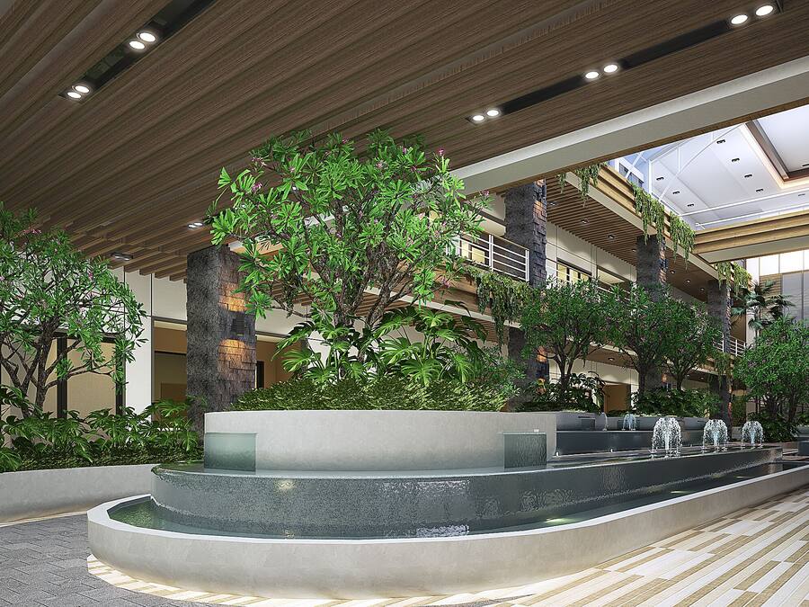 Un moderno atrio interior con una fuente central, varios niveles de balcones y abundante vegetación.