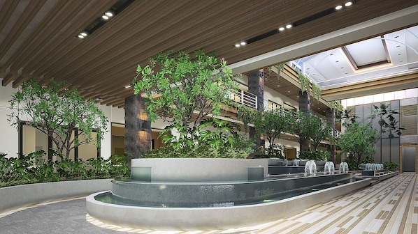 A modern indoor atrium with a central water feature, multiple levels of balconies, and lush greenery. - Grand Swiss-Belhotel Harbour Bay (Batam)