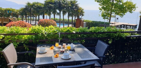 Una mesa lista para el desayuno, con vistas al mar y palmeras.