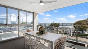 Un balcone con tavolo e sedie, un lanterne decorativo e vista sull'acqua e sullo skyline della città.
