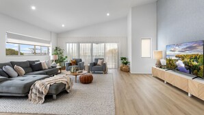 A modern living room with a grey sofa, armchairs, a coffee table, and a TV on a wooden cabinet.