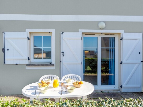 A patio with a table set for breakfast, two windows with shutters, and a door with glass panels. - Pentrez Cottage - 600m de la Plage (Saint-Nic)