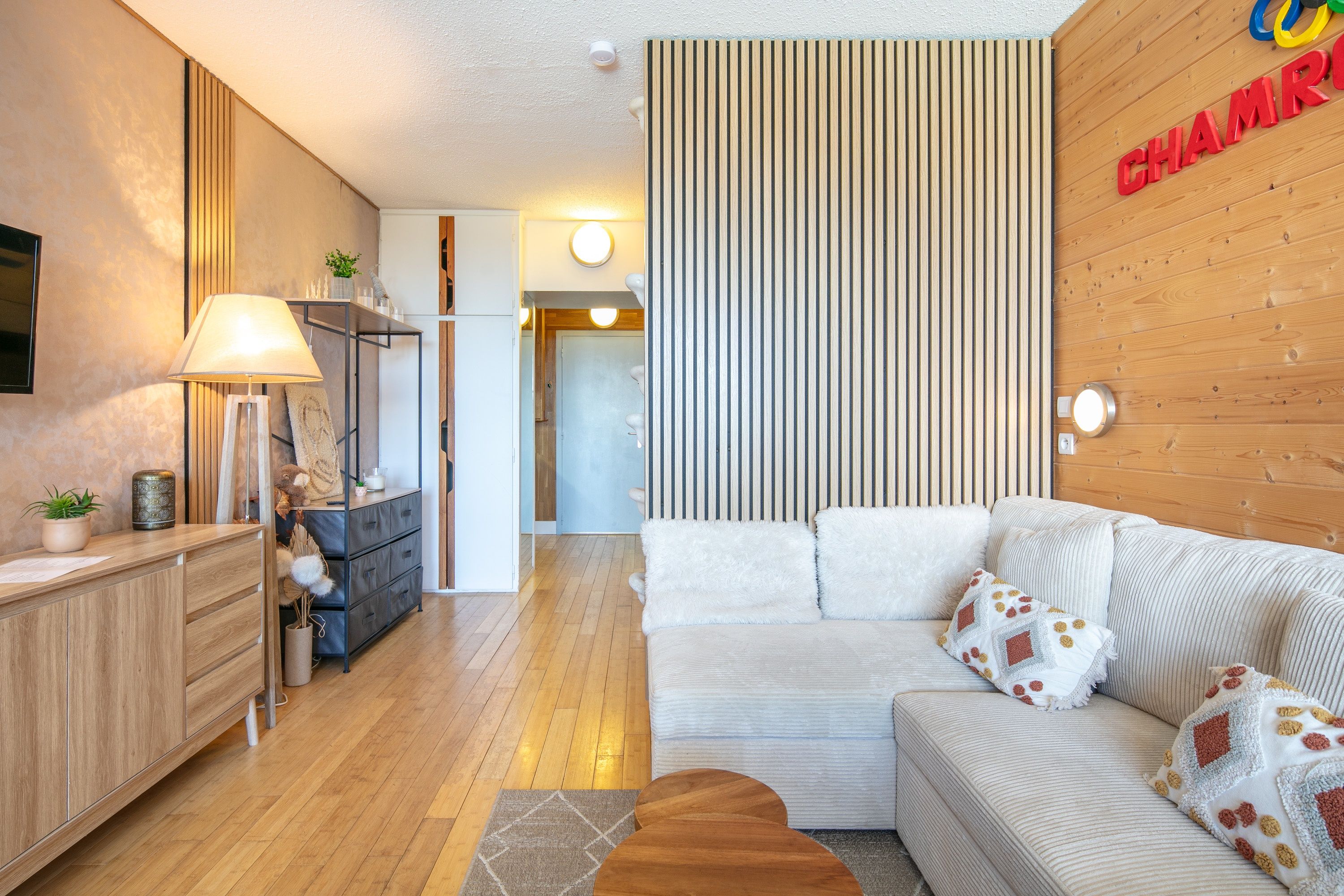 Una sala de estar moderna con un sofá, una lámpara y una pared de madera con un diseño de rayas verticales.